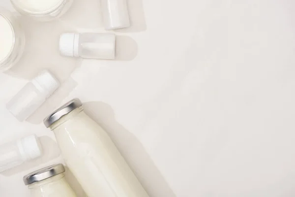 Top view of glasses and bottles of homemade yogurt near containers with starter cultures on white background — Stock Photo