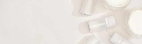 Vista superior de copos de iogurte caseiro perto de recipientes com culturas iniciais no fundo branco, tiro panorâmico — Fotografia de Stock