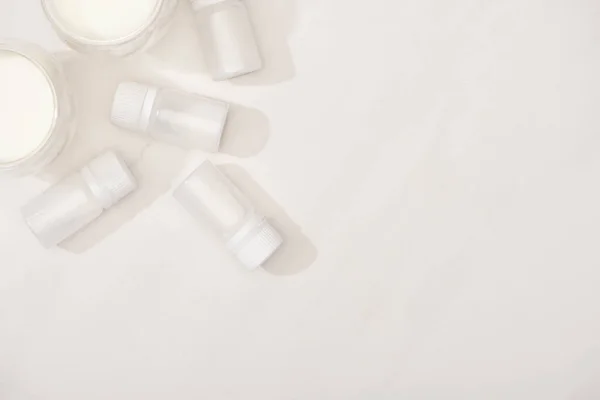 Vue du dessus des verres de yaourt maison près des conteneurs avec des cultures de démarrage sur fond blanc — Photo de stock