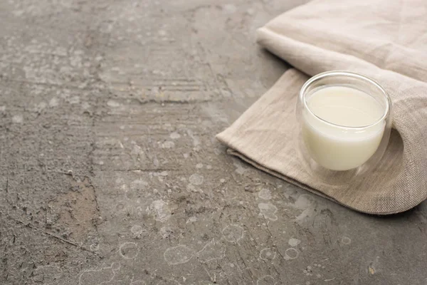 Vista ad alto angolo di vetro di yogurt fatto in casa su tessuto beige su sfondo grigio — Foto stock