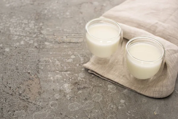 Vista en ángulo alto de vasos de yogur casero sobre tela beige sobre fondo gris - foto de stock