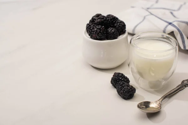 Selective focus of sugar bowl with blackberries near glass of homemade yogurt and teaspoon on white background — Stock Photo