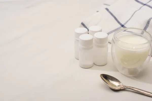 Glass of homemade yogurt near teaspoon, containers with starter cultures and cloth on white background — Stock Photo