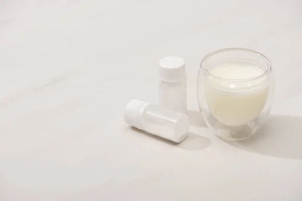 Hochwinkelansicht des Glases hausgemachten Joghurts in der Nähe von Behältern mit Starterkulturen auf weißem Hintergrund — Stockfoto