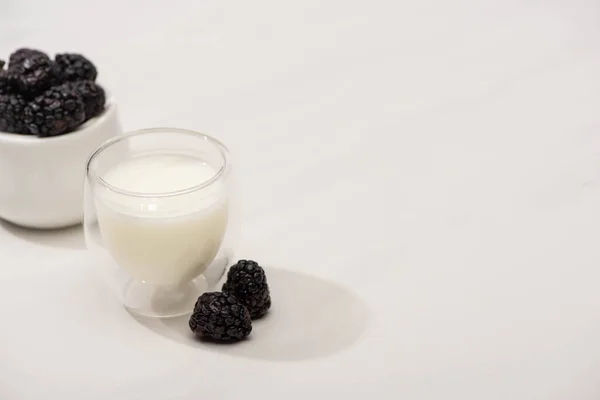 Высокий угол обзора сахарной чаши с ежевикой и стаканом домашнего йогурта на белом фоне — стоковое фото