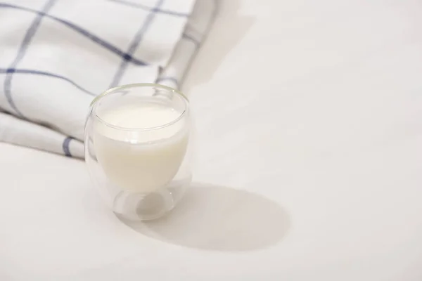 Vista de alto ângulo de vidro de iogurte caseiro perto de tecido xadrez no fundo branco — Fotografia de Stock