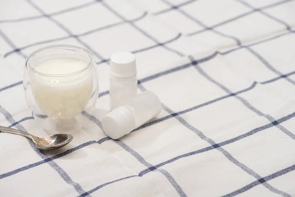 Hochwinkelblick auf Glas mit hausgemachtem Joghurt, Teelöffel und Behältern mit Starterkulturen auf kariertem Stoff — Stockfoto