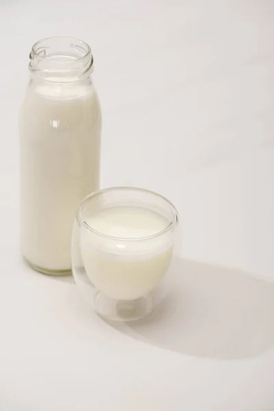 Vista ad alto angolo di bottiglia e vetro di yogurt fatto in casa su sfondo bianco — Foto stock