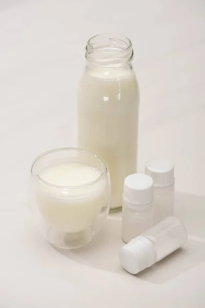 Blick auf Flasche und Glas hausgemachten Joghurt in der Nähe von Behältern mit Starterkulturen auf weißem Hintergrund — Stockfoto