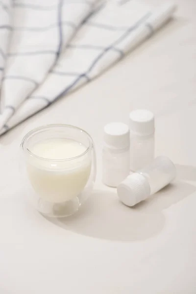 Foco seletivo de vidro de iogurte caseiro e recipientes com culturas iniciais perto de tecido no fundo branco — Fotografia de Stock