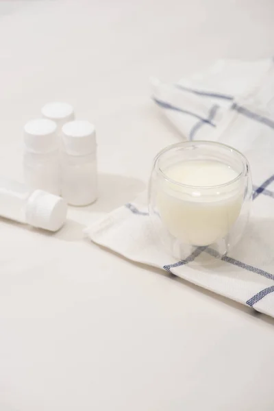 Concentration sélective du verre de yaourt fait maison sur le tissu près des conteneurs avec des cultures de démarrage sur blanc — Photo de stock