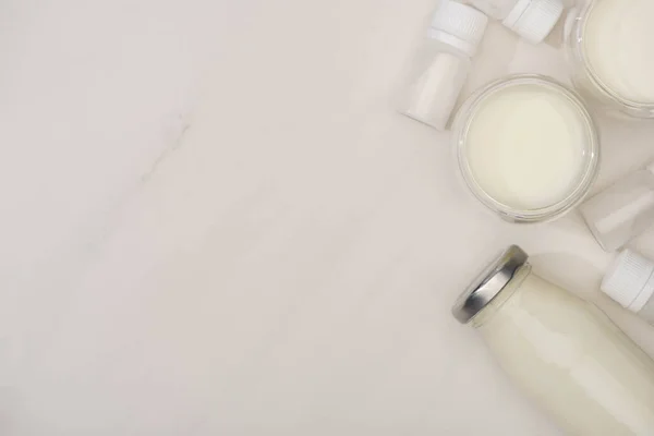 Top view of bottle and glasses of homemade yogurt and containers with starter cultures on white background — Stock Photo