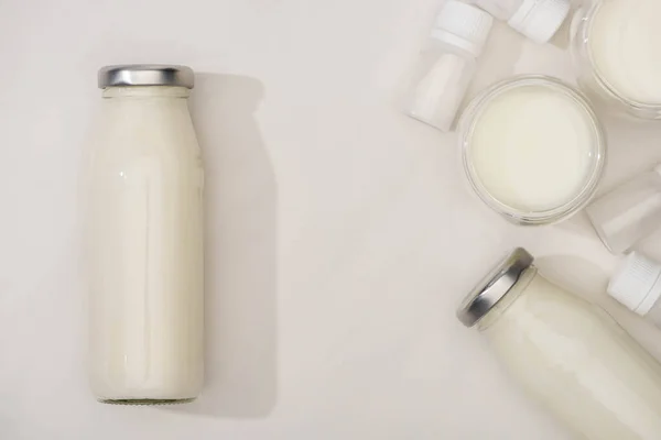 Vista dall'alto di bottiglie e bicchieri di yogurt e contenitori fatti in casa con colture di antipasto su sfondo bianco — Foto stock