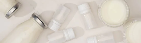 Top view of bottles and glasses of homemade yogurt near containers with starter cultures on white, panoramic shot — Stock Photo