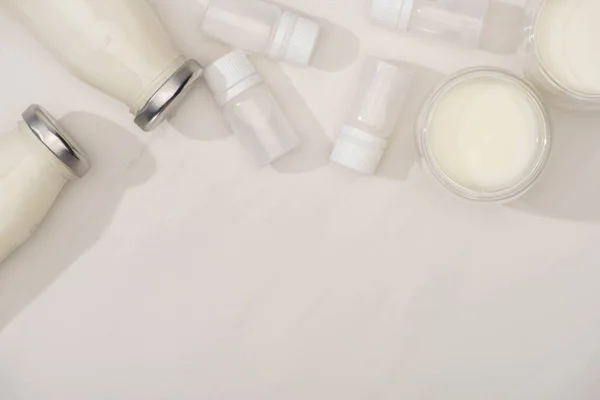Vue du dessus des bouteilles et des verres de yaourt près des conteneurs avec des cultures de démarrage sur blanc — Photo de stock