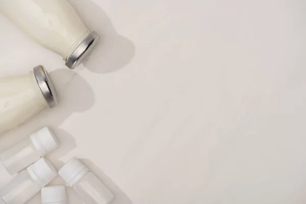 Top view of containers with starter cultures and bottles of homemade yogurt on white — Stock Photo