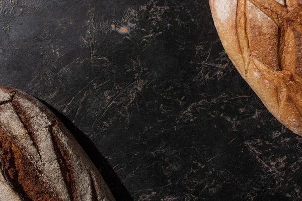 Top view of fresh baked white and brown bread on stone black surface — Stock Photo