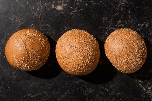 Top view of fresh baked sesame buns on stone black surface — Stock Photo