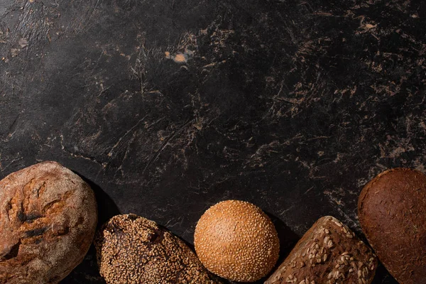 Vista superior do pão cozido no forno fresco na superfície preta de pedra — Fotografia de Stock