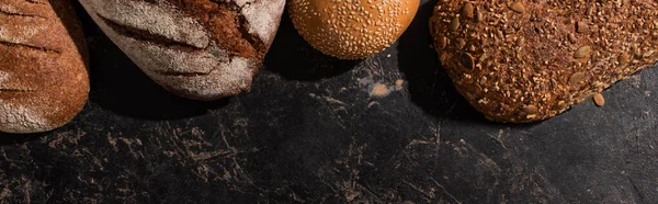 Top view of fresh baked bread on stone black surface, panoramic shot — Stock Photo