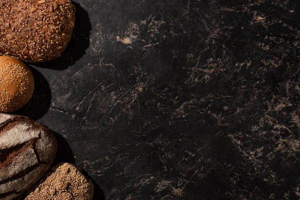 Vue de dessus du pain frais cuit sur la surface noire de pierre — Photo de stock