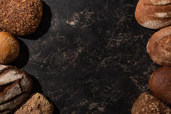 Vista superior de pan de grano entero recién horneado en la superficie de piedra negro - foto de stock