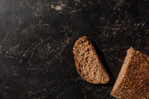 Vista dall'alto del pane integrale tagliato su pietra superficie nera — Stock Photo