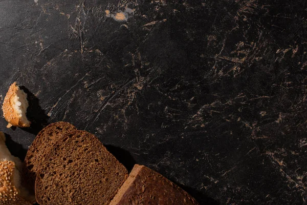 Top view of cut brown bread on stone black surface — Stock Photo