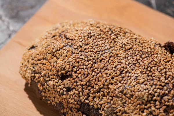 Pane nero appena sfornato con sesamo sul tagliere — Foto stock