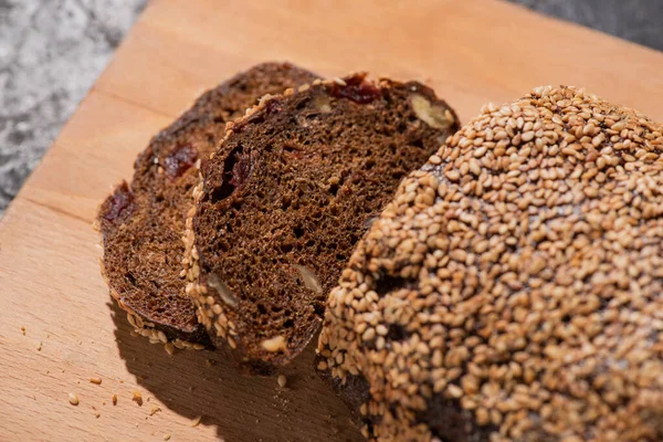 Frisch gebackenes Schwarzbrot mit Sesam auf Schneidebrett — Stockfoto