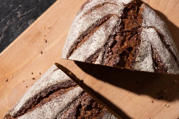Vista superior del pan marrón recién horneado en la tabla de cortar - foto de stock