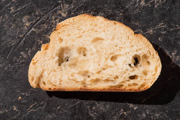 Vista superior da fatia de pão branco assado fresco na superfície preta de pedra — Fotografia de Stock
