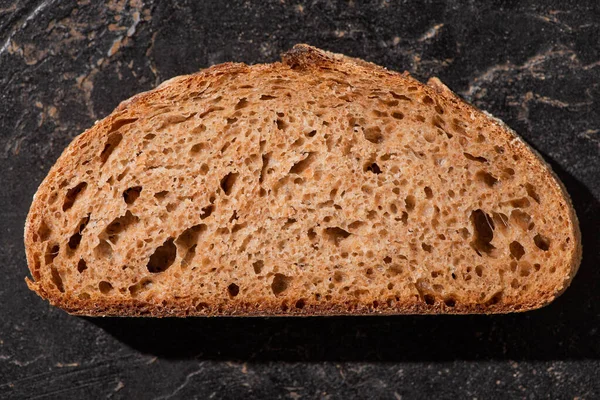 Vista superior da fatia de pão marrom na superfície preta de pedra — Fotografia de Stock