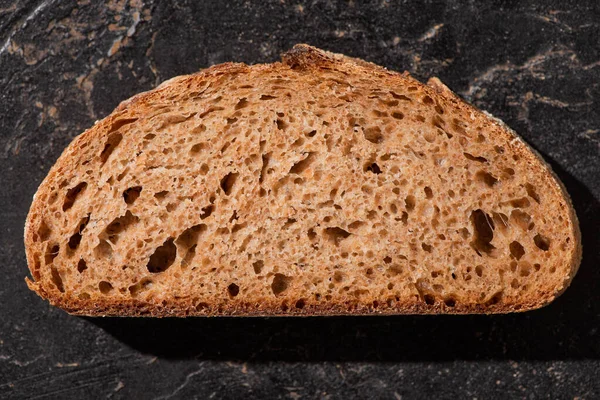 Vista dall'alto di fetta di pane marrone su pietra superficie nera — Foto stock