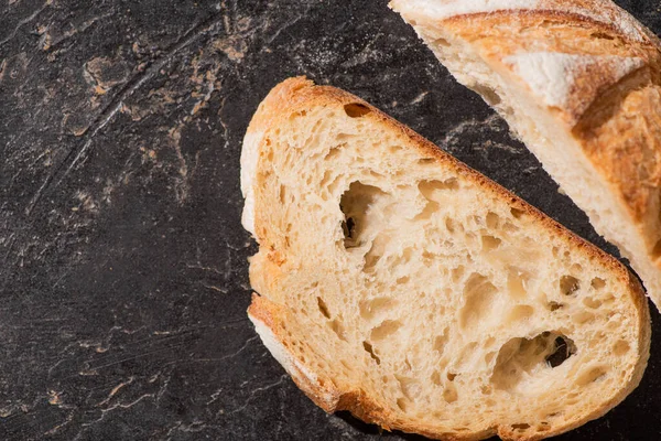 Vista dall'alto del pane bianco appena sfornato tagliato sulla superficie nera di pietra — Foto stock