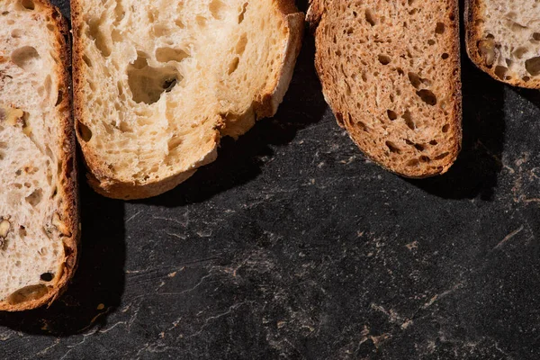 Vista dall'alto di fette di pane appena sfornate su superficie nera di pietra — Foto stock