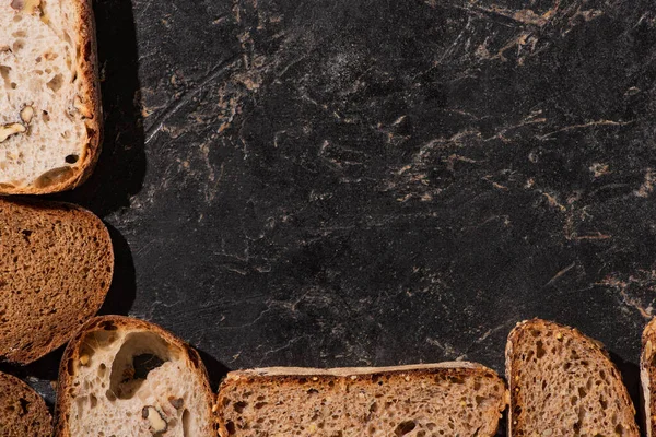 Top view of fresh baked bread slices on stone black surface — Stock Photo