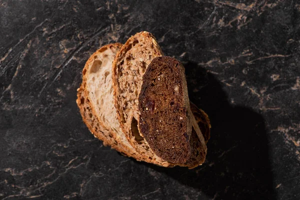 Vista superior de rebanadas de pan recién horneado en la superficie de piedra negro - foto de stock