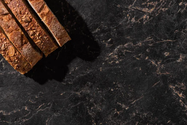 Vista dall'alto di fette di pane fresco su superficie nera di pietra — Foto stock