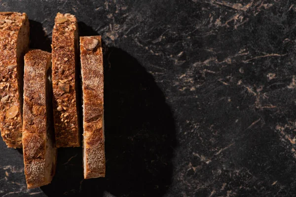 Vista superior de fatias de pão fresco na superfície preta de pedra — Fotografia de Stock