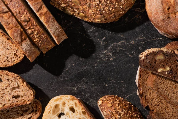 Draufsicht auf frische Brotscheiben auf steinschwarzer Oberfläche — Stockfoto