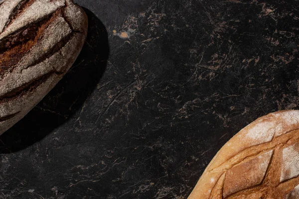 Top view of fresh baked brown and white bread on stone black surface — Stock Photo