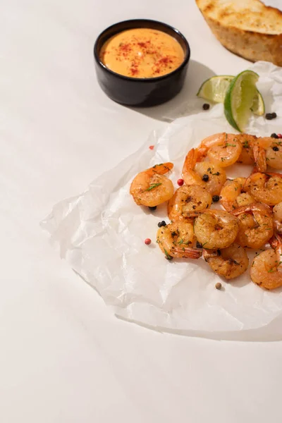 Fried shrimps on parchment paper with sauce and lime on white background — Stock Photo