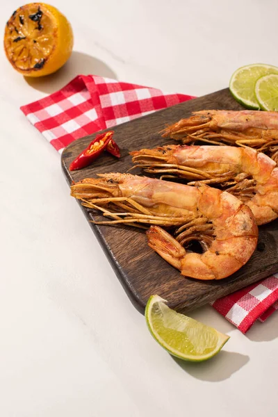 Fried shrimps on wooden board on plaid napkin with sauce and lime on white background — Stock Photo