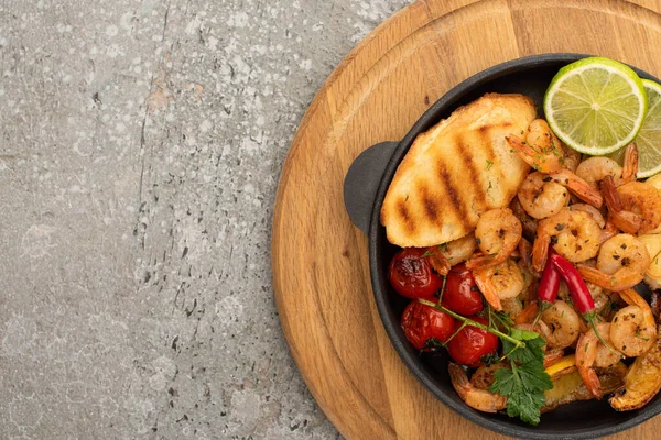 Vue de dessus des crevettes frites avec des toasts grillés, légumes et citron vert sur fond de béton gris — Photo de stock