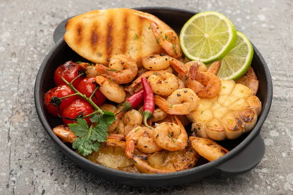 Fried shrimps with grilled toasts, vegetables and lime on grey concrete background — Stock Photo