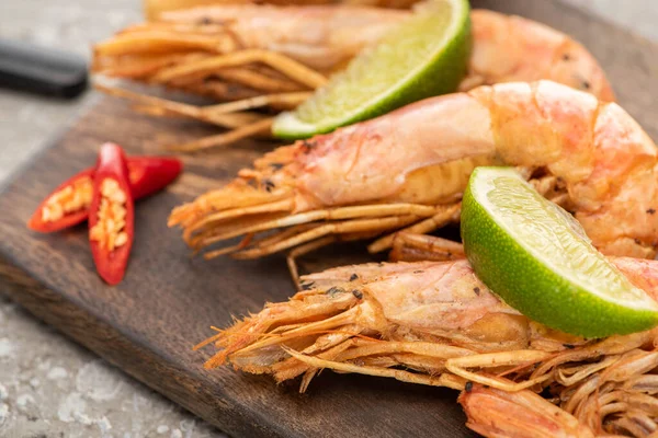 Close up view of fried shrimps with chili and lime on wooden board — Stock Photo