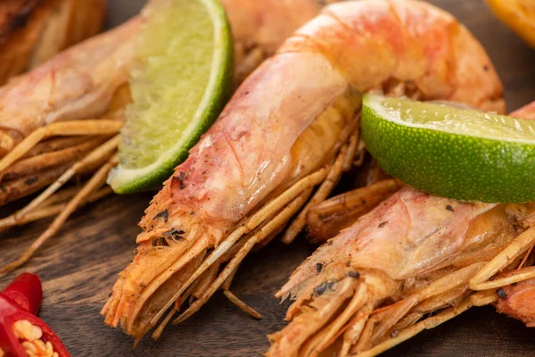 Close up view of fried shrimps with chili and lime on wooden board — Stock Photo