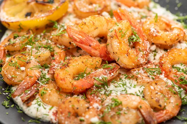 Close up view of fried shrimps in sauce with dill and lemon in black plate — Stock Photo