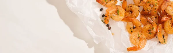 Top view of fried shrimps on parchment paper with pepper on white background, panoramic shot — Stock Photo